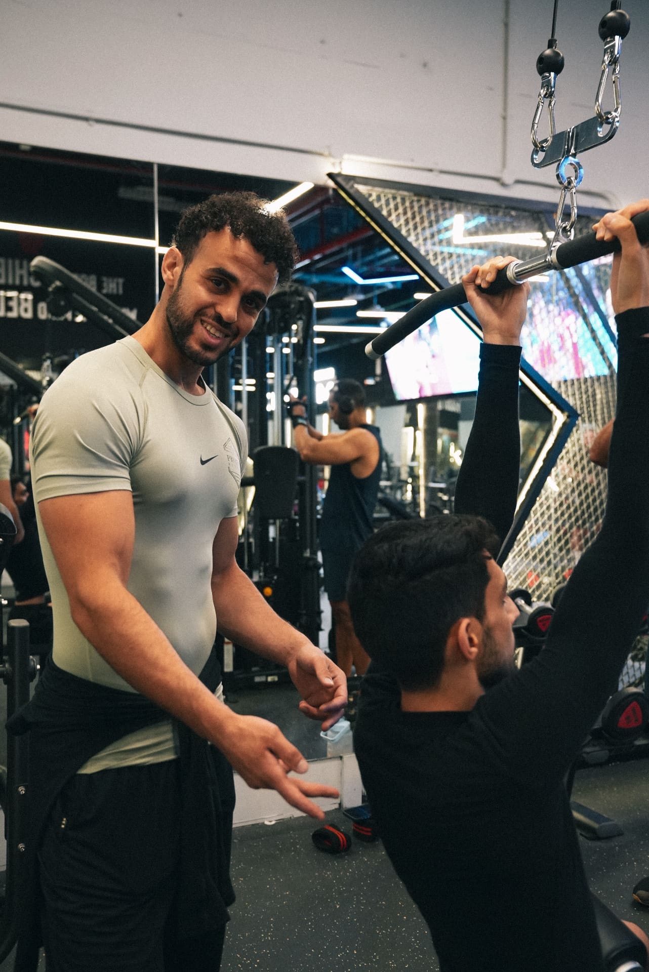 Coach smiling while spotting a client on the lat pulldown